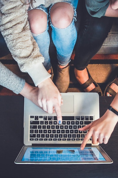 three person pointing the silver laptop computer