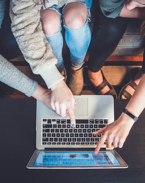 three person pointing the silver laptop computer