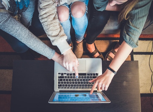 three person pointing the silver laptop computer