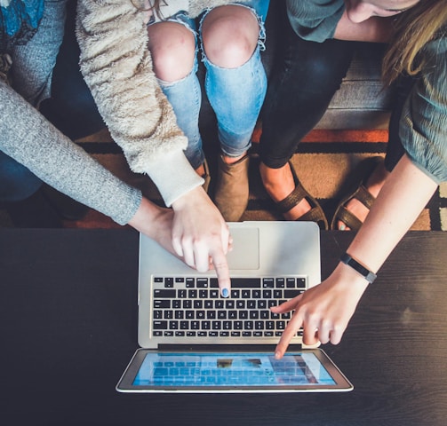 three person pointing the silver laptop computer