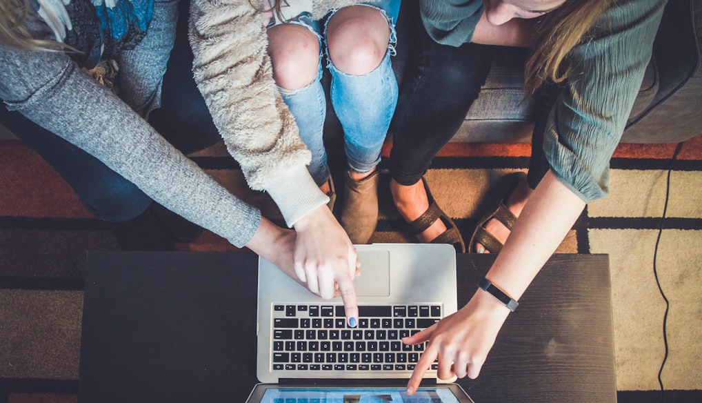 three person pointing the silver laptop computer