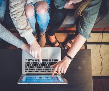 three person pointing the silver laptop computer