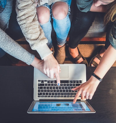 three person pointing the silver laptop computer