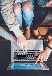 three person pointing the silver laptop computer