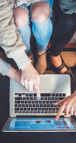 three person pointing the silver laptop computer