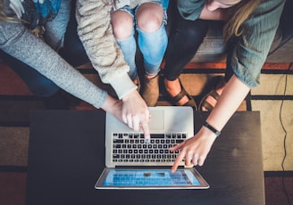 three person pointing the silver laptop computer