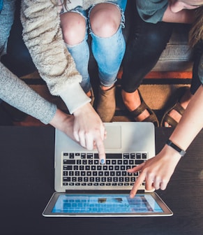 three person pointing the silver laptop computer