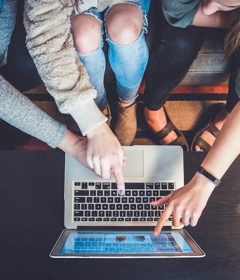 three person pointing the silver laptop computer