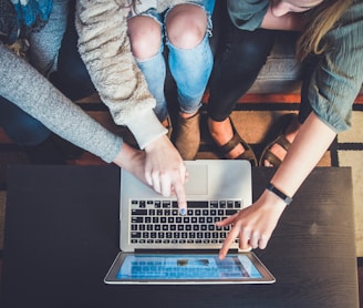 three person pointing the silver laptop computer