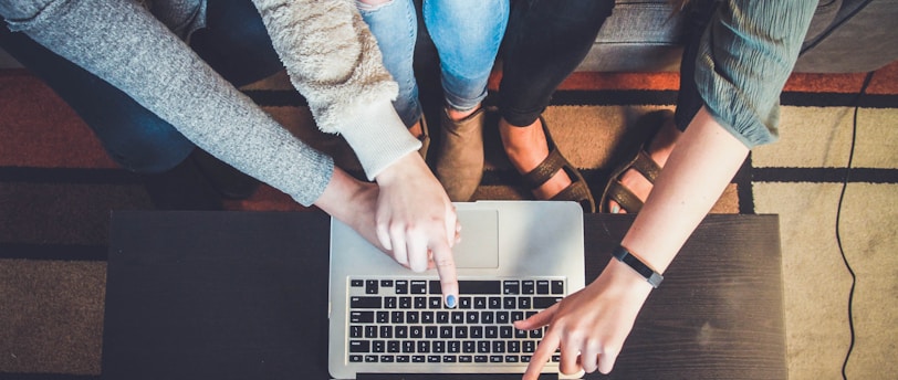 three person pointing the silver laptop computer