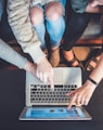 three person pointing the silver laptop computer