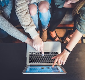 three person pointing the silver laptop computer