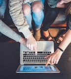 three person pointing the silver laptop computer