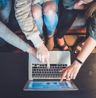 three person pointing the silver laptop computer