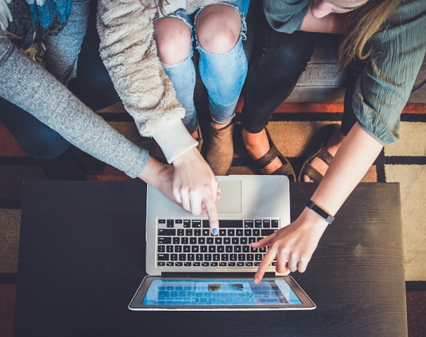 three person pointing the silver laptop computer