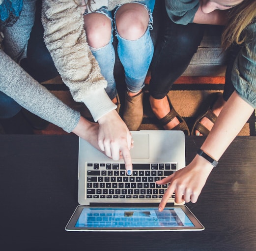 three person pointing the silver laptop computer