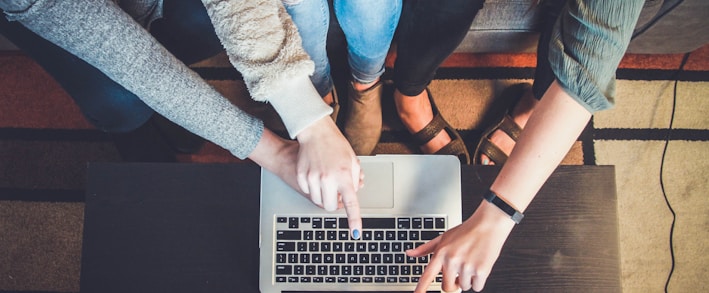 three person pointing the silver laptop computer