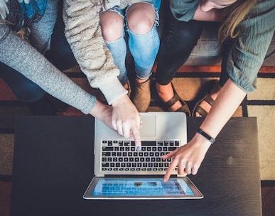 three person pointing the silver laptop computer