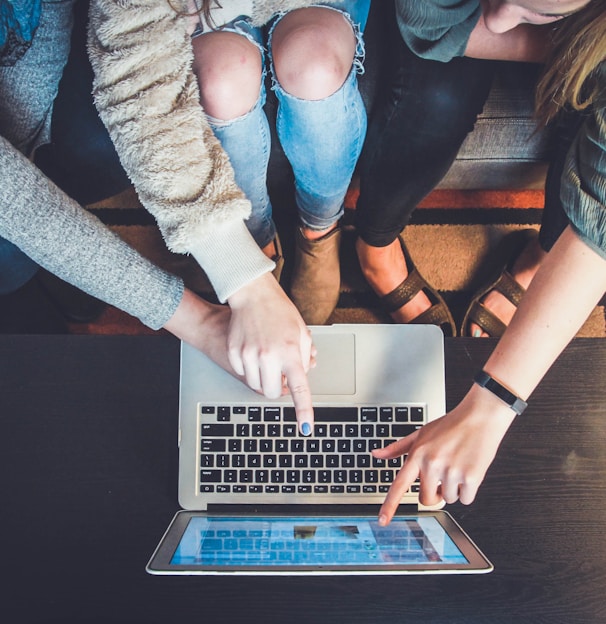 three person pointing the silver laptop computer