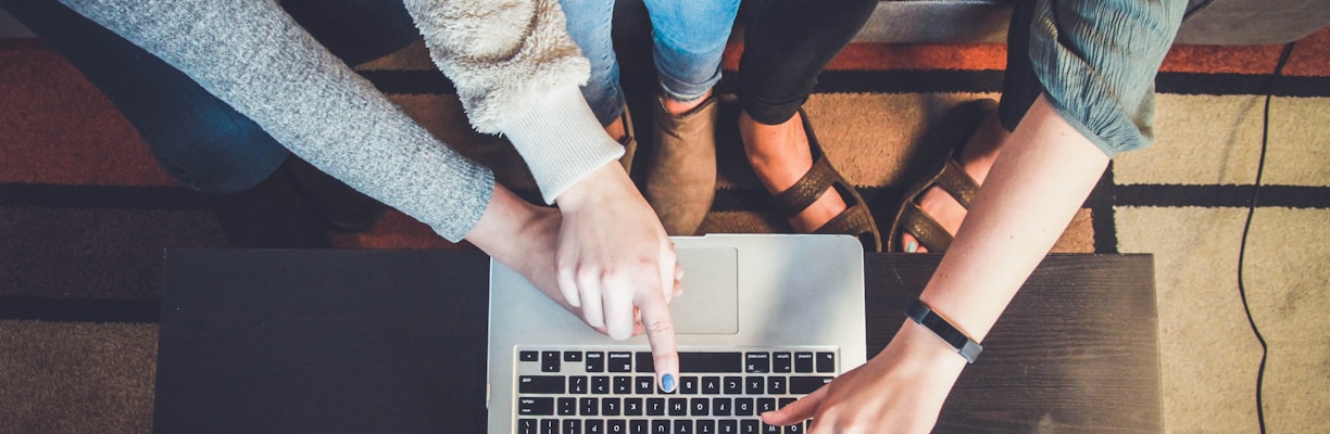 three person pointing the silver laptop computer