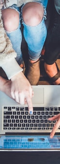 three person pointing the silver laptop computer