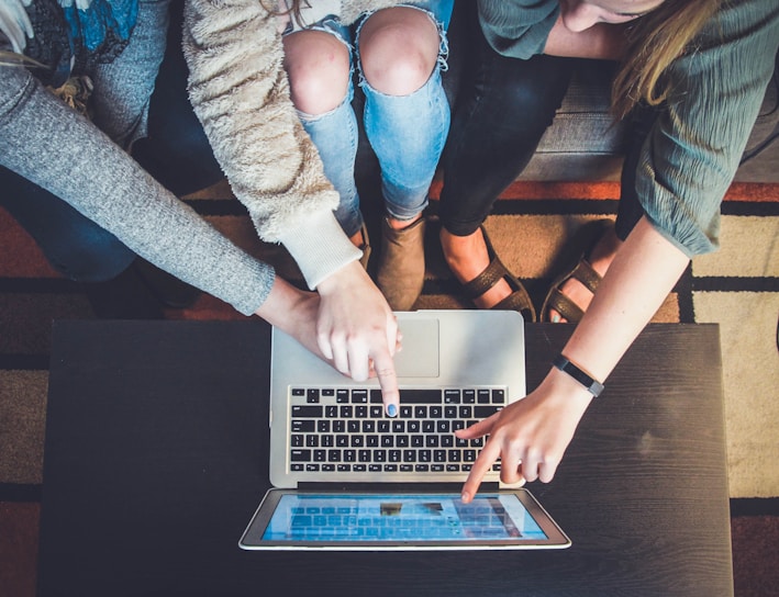 three person pointing the silver laptop computer