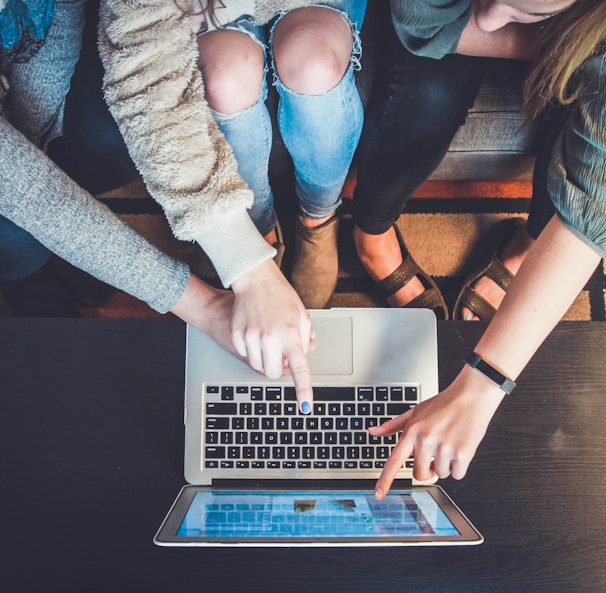 three person pointing the silver laptop computer