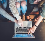 three person pointing the silver laptop computer