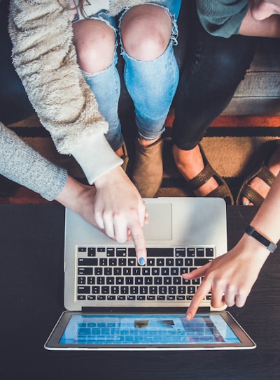 three person pointing the silver laptop computer