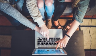 three person pointing the silver laptop computer