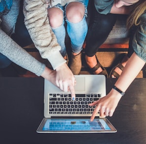 three person pointing the silver laptop computer