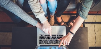 three person pointing the silver laptop computer