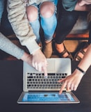 three person pointing the silver laptop computer