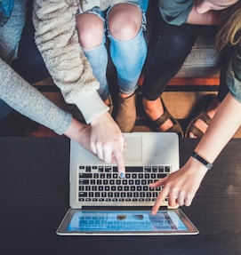 three person pointing the silver laptop computer