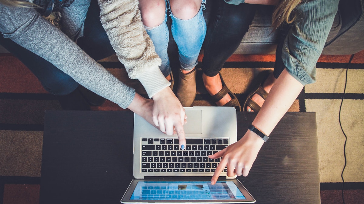 three person pointing the silver laptop computer