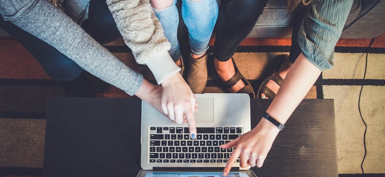 three person pointing the silver laptop computer