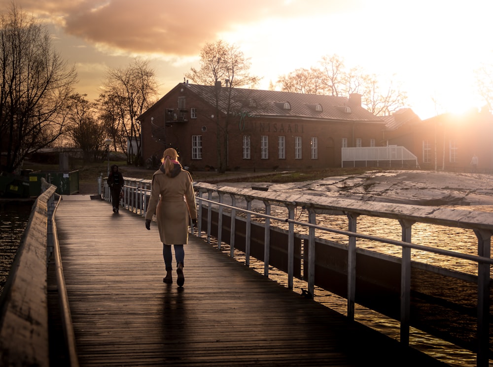 man and woman walking on wooden bridge during sunset