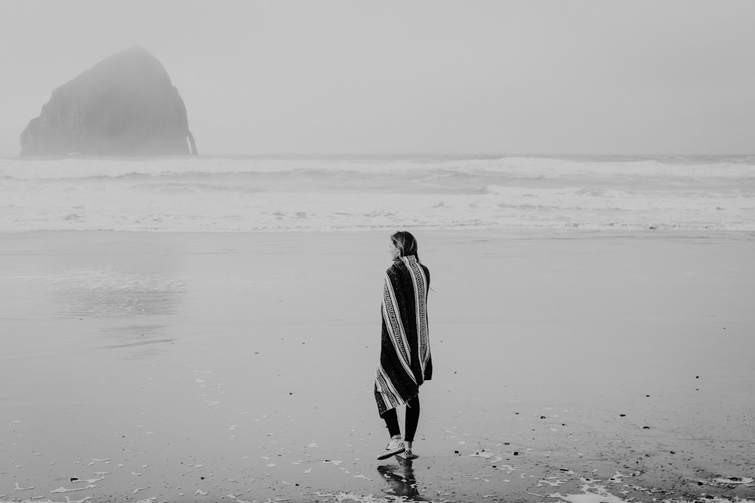 grayscale photo of woman standing on shore