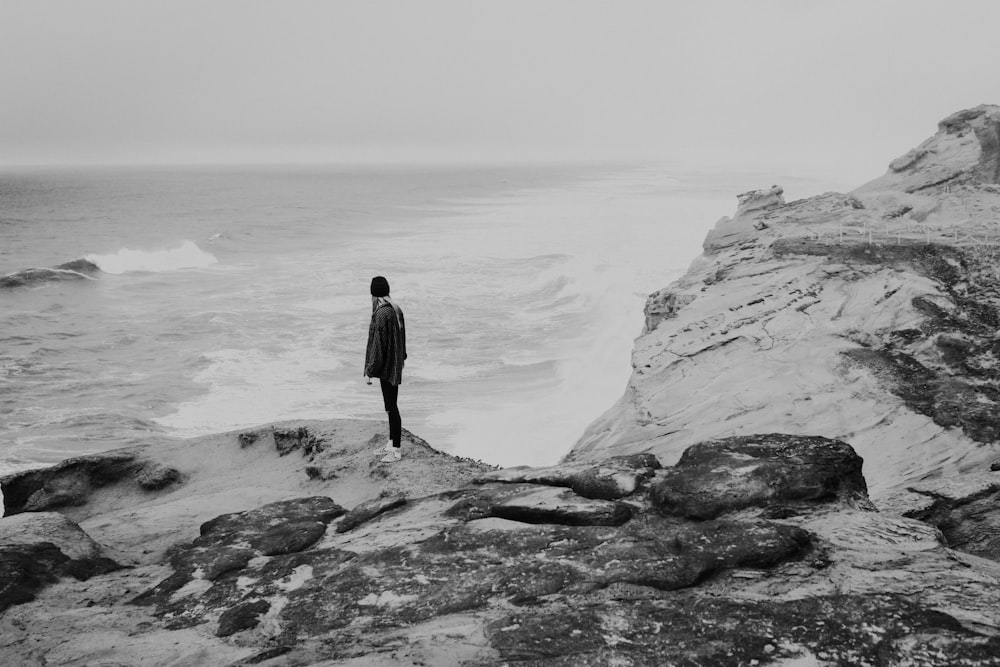 person standing on rock near seashore