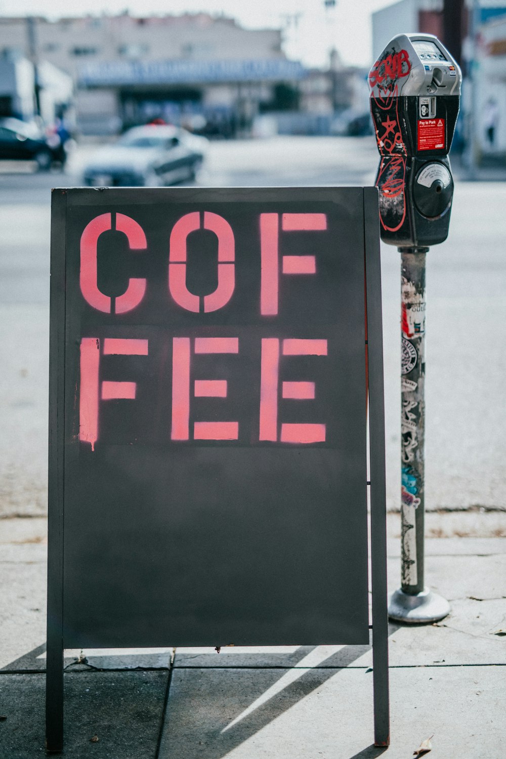 Segnaletica autoportante nera con stampa caffè accanto allo slot di parcheggio a gettoni