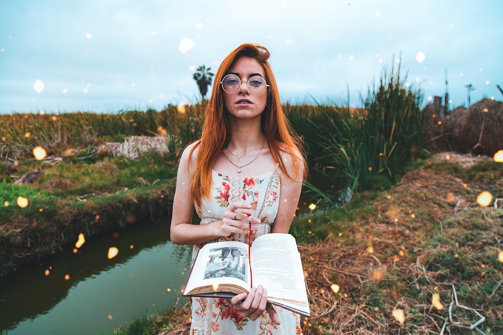 woman holding an open book near the creek