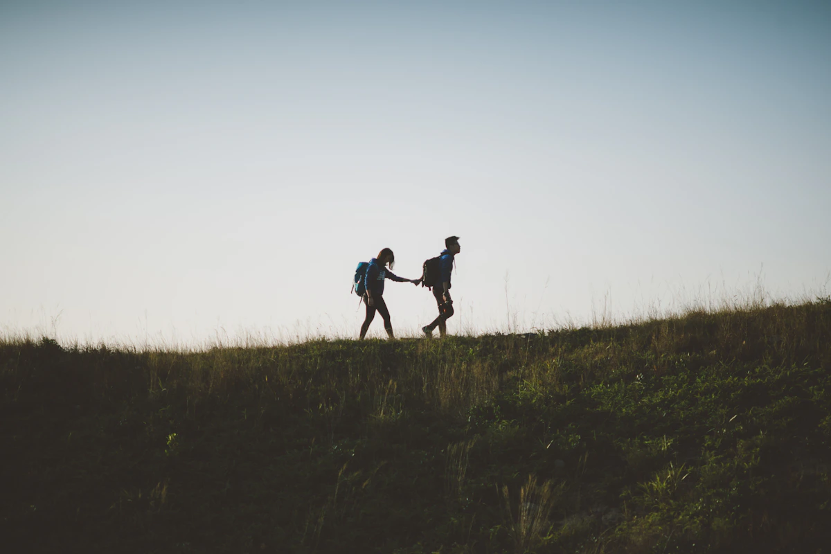 Two people walking hand in hand through a peaceful green landscape