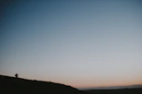 Wide shot of an Angolan landscape at dusk, with a lone figure filming.