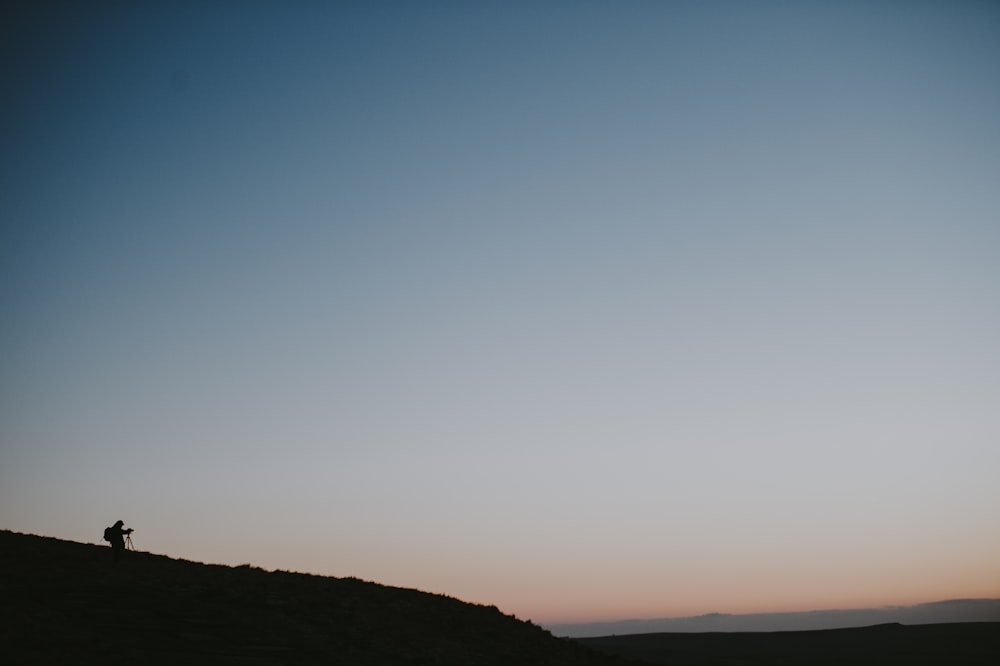 person standing on hill under blue sky