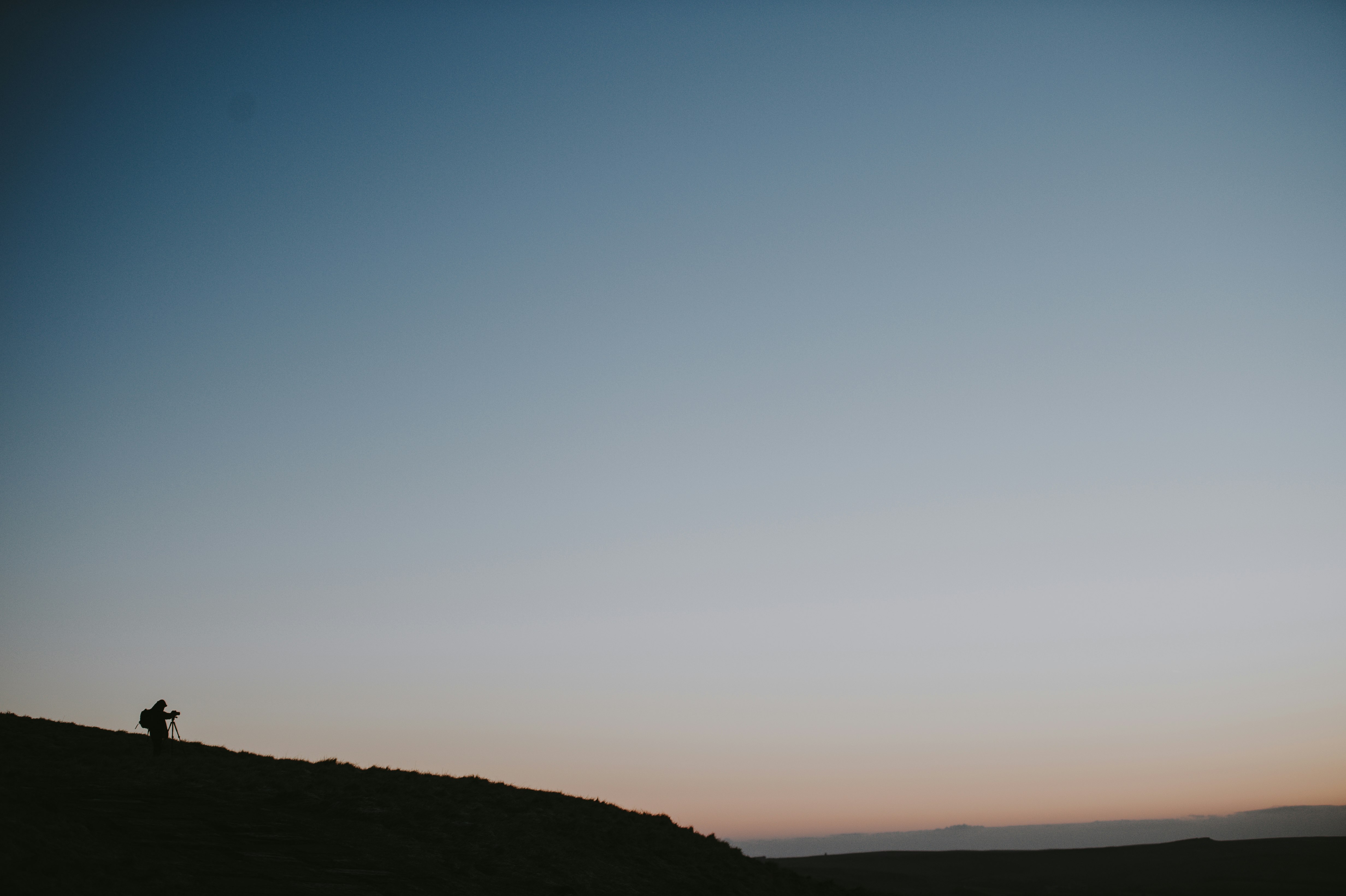 person standing on hill under blue sky