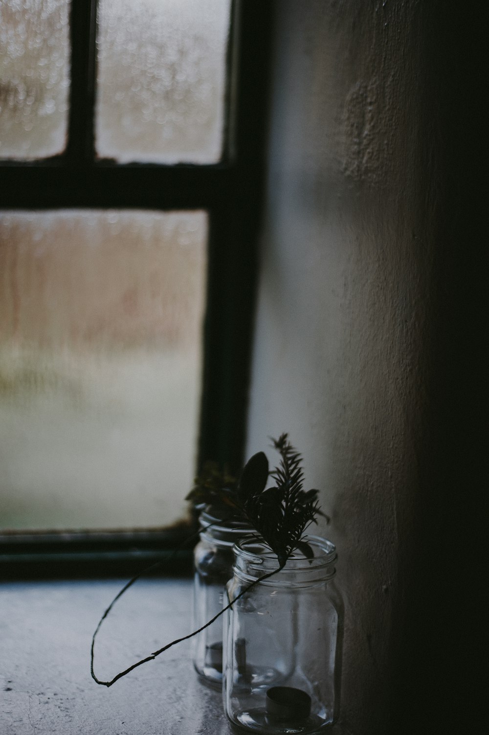 two clear glass jars near window