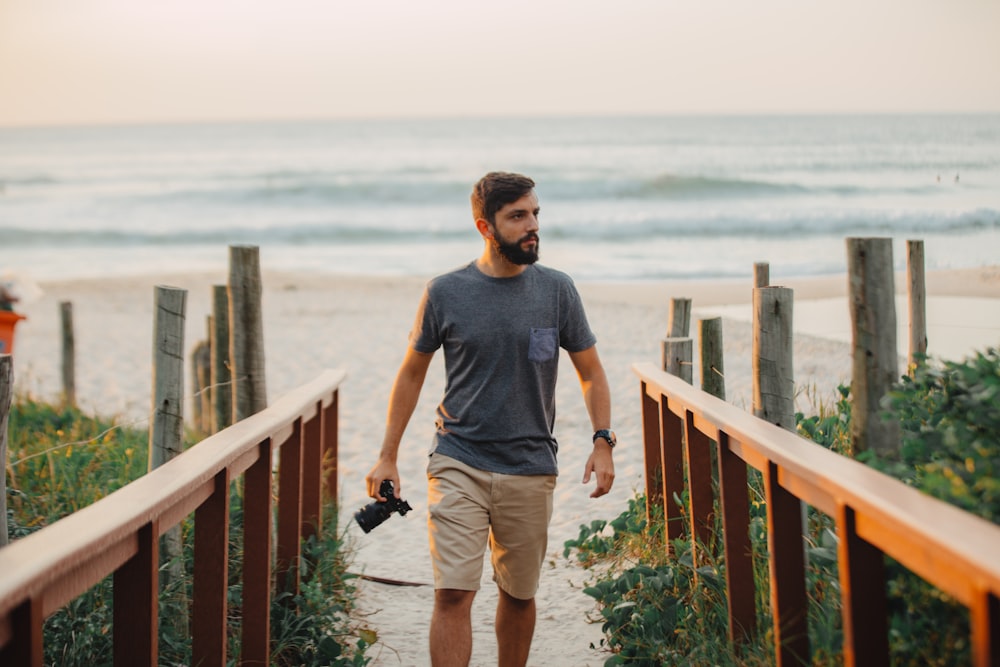 man walking holding camera near shoreline