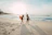 two women walking towards the ocean carrying surfboards during day