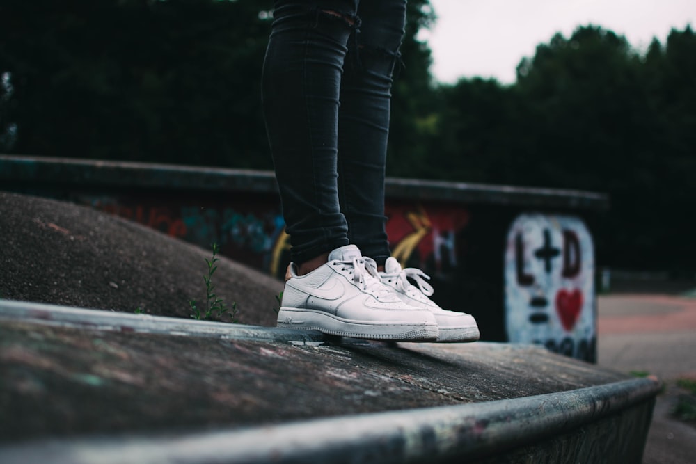 woman standing and wearing white Nike low-top sneakers