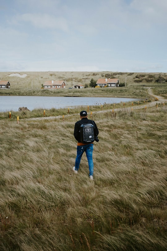 person wearing blue denim skinny jeans and black jacket walking on the grass in Ushuaia Argentina